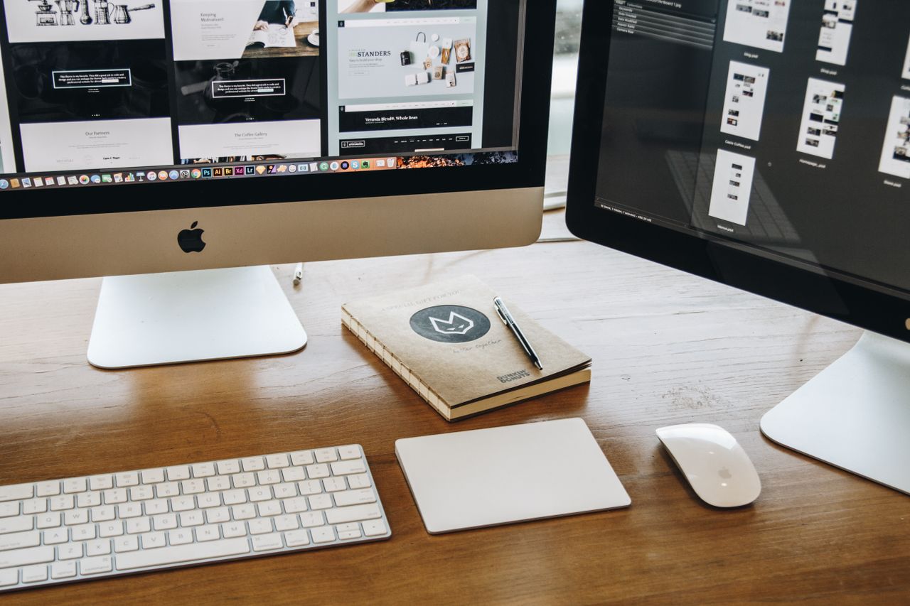 Un bureau épuré équipé de deux écrans, clavier, souris et carnet, idéal pour une productivité optimale.
